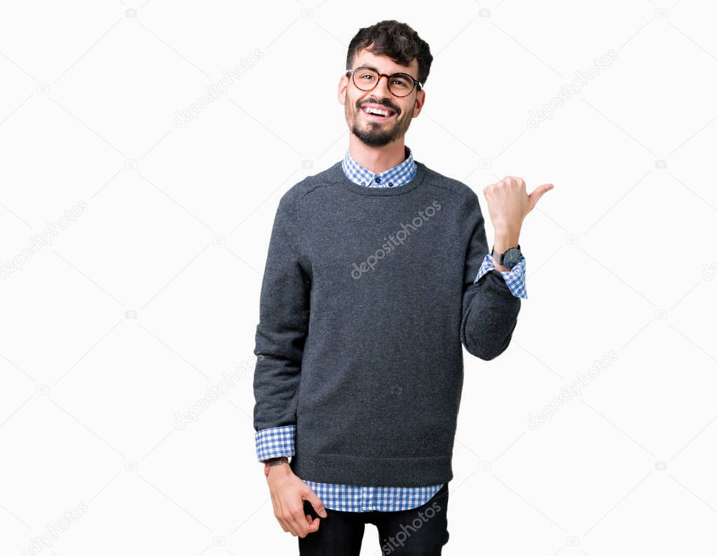 Young handsome smart man wearing glasses over isolated background smiling with happy face looking and pointing to the side with thumb up.