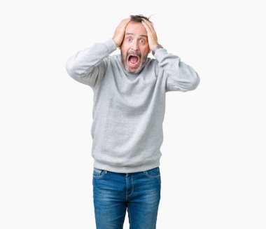 İzole arka planda bir sweatshirt giyen yakışıklı Orta Çağ kıdemli adam çılgın ve baş elleri ile korkuyor, korku ve açık ağız ile şok şaşırttı