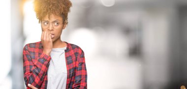 Stresli ve gergin elle çivi ısırma ağzına bakarak izole arka plan üzerinde gözlük güzel genç Afro-Amerikan kadın. Anksiyete sorunu.