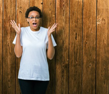 Güzel genç Afro-Amerikan kadın üzerinde gözlük takan deli kutluyor arka plan izole ve silah ile başarı için yükseltilmiş ve açık gözleri heyecanlı çığlık hayrete düşürdü. Kazanan kavramı