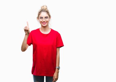 Kırmızı t-shirt ve gözlük ve parmak gülümseyen süre bir numara ile kendinden emin ve mutlu yukarıyı gösteren izole arka plan üzerinde giyen genç güzel sarışın kadın.