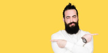 Uzun saç ve sakal sportif sweatshirt giyen genç hipster adamla her iki parmak ile işaret eden, farklı yönde katılmıyorum