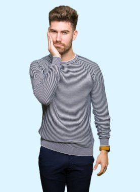 Çizgi kazak giyen genç yakışıklı adam yorgun bakıyor ve çapraz silah ile depresyon sorunları ile sıkılmış düşünme.