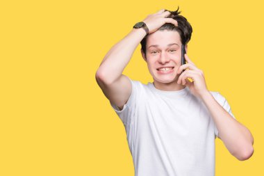 Smartphone kafa üzerinde el ile vurguladı izole arka plan üzerinde konuşan genç adam şok utanç ve sürpriz suratla, öfkeli ve sinirli. Korku ve hata için üzgün.