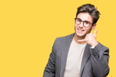 İşin gülümseyen izole arka plan üzerinde gözlüklü genç iş adamı telefon hareketi ile el ve parmak telefonda konuşuyor gibi. Kavramları iletişim.