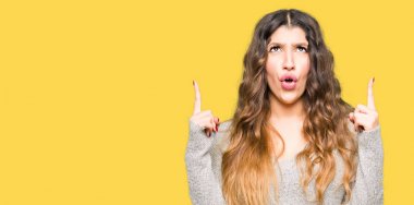 Kış elbise giyen genç güzel kadın hayrete ve yukarıya bakıp parmakları ile işaret şaşırttı ve silah kaldırdı.