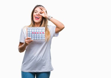 Adet takvim ile mutlu yüz el parmaklarının arasından seyir göz üzerinde ok işaretiyle yapıyor gülümseyen izole arka plan üzerinde tutan genç güzel kadın