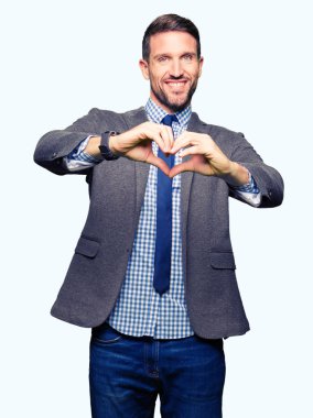 Takım elbise ve kravat aşık kalp simgesi ve elleriyle şekil gösteren gülümseyen giymiş yakışıklı iş adamı. Romantik kavramı.