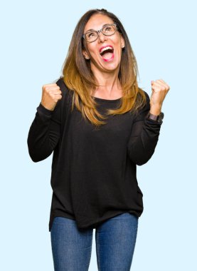 Gülümseyen ve başarı için çığlık çok mutlu ve heyecanlı kaldırdı, silah ile kazanan jest yapıyor gözlüklü güzel orta yaş kadın. Kutlama kavramı.