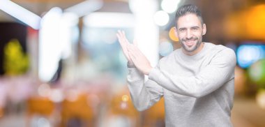 Genç yakışıklı adam giyen kazak izole üzerinde arka plan Clapping ve mutlu ve neşeli, gururlu gülümseyen birlikte eller alkış