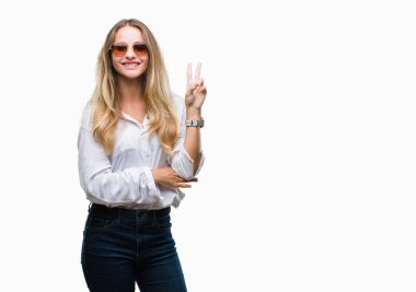 Genç güzel sarışın kadın mutlu yüz zafer işareti yaparken kameraya göz kırpıyor ile gülümseyen izole arka plan üzerinde güneş gözlüğü takıyor. İki numaralı.