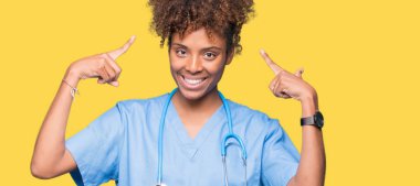 Genç Afro-Amerikan doktor kadın izole arka plan hem el parmak, harika bir fikir ya da düşünce, iyi bellek ile baş gösteren gülümseyen