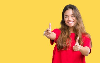 Fotoğraf makinesi ile mutlu ve komik yüz için parmakları işaret izole arka plan üzerinde kırmızı t-shirt giyen genç güzel esmer kadın. İyi enerji ve vibes.