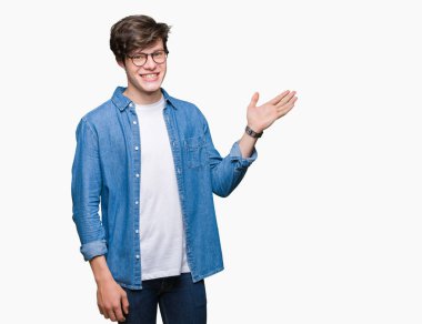 Neşeli sunulması ve kameraya bakarak avucunun ile işaret gülümseyen izole arka plan üzerinde gözlük takan genç yakışıklı adam.