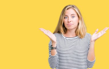 Üzerinde çizgili süveter giyen güzel genç kadın arka plan clueless ve şaşkın bir ifadeyle kollar ve eller kaldırdı izole. Şüphe kavramı.