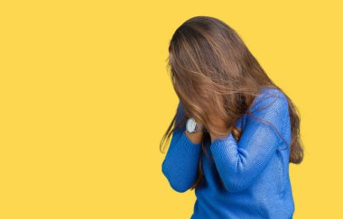 Yüz eller ile ağlayarak süre kapsayan üzgün ifade ile izole arka plan üzerinde mavi kazak giyen genç güzel esmer kadın. Depresyon kavramı.