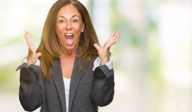 Büyük boy erkek giyen orta yaş yetişkin kadın deli kutluyor izole arka plan üzerinde ceket ve silah ile başarı için yükseltilmiş ve açık gözleri heyecanlı çığlık hayrete düşürdü. Kazanan kavramı