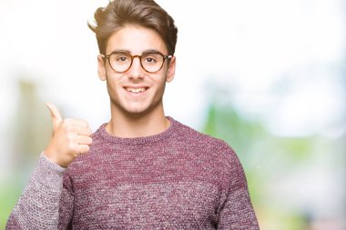 Hareketi el ile mutlu yaşasın yapıyor izole arka plan üzerinde gözlük takan yakışıklı delikanlı. Başarı gösteren kameraya bakarak ifade onaylama.