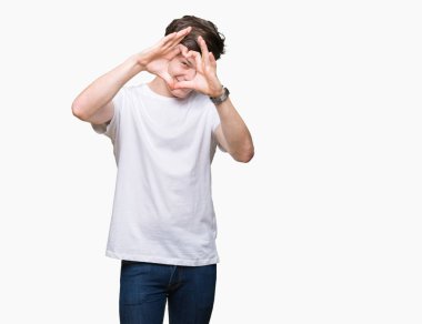 El ve parmak işareti seyir gülümseyen izole arka plan yapıyor kalp şekli üzerinde rahat beyaz t-shirt giyen genç yakışıklı adam