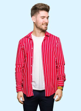 Kırmızı gömlek giyen genç yakışıklı adam yüzünde gülümseme ile yan bakmak, doğal ifade. Güven gülüyor.