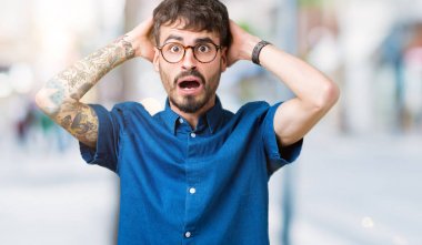 Üzerinde gözlük takan genç yakışıklı adam arka plan deli izole ve baş, korkuyor ve açık ağzı ile şok sürpriz elleriyle korkuttu