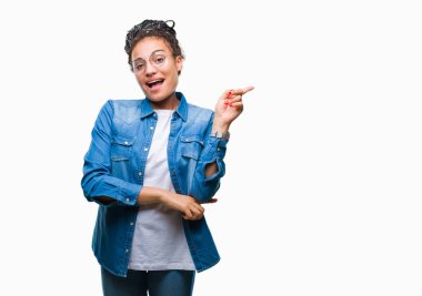 Kameraya bakarak yan el ve parmak ile işaret yüzünde kocaman bir gülümseme ile izole arka plan üzerinde gözlük takan saç Afro-Amerikan kız Genç örgülü.