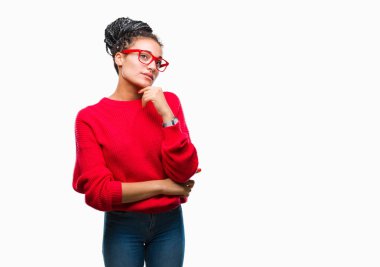 Genç kazak giyen Afro-Amerikan kız saç örgülü ve gözlük el ile izole arka plan üzerinde soru, dalgın ifade düşünmeye çene. Düşünceli yüzüyle gülümsüyor. Şüphe kavramı.