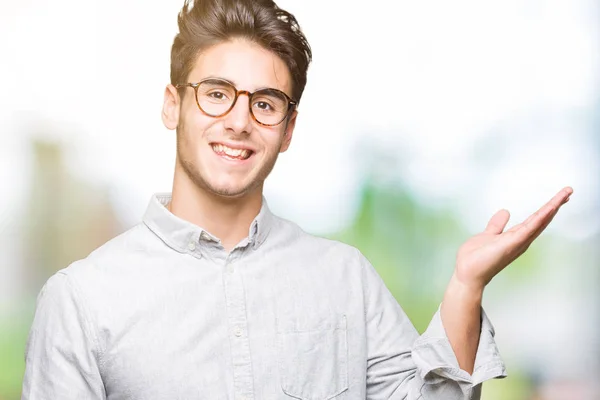 Ung Flot Mand Iført Briller Isoleret Baggrund Smilende Munter Præsentere - Stock-foto