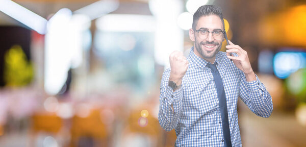 Young business man talking on the phone over isolated background screaming proud and celebrating victory and success very excited, cheering emotion