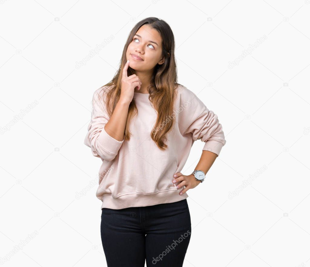 Young beautiful brunette woman wearing pink sweatshirt over isolated background with hand on chin thinking about question, pensive expression. Smiling with thoughtful face. Doubt concept.