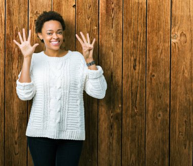 Güzel genç Afro-Amerikan kadın giyiyor kazak gösterilen ve parmakları ile işaret izole arka plan üzerinde numara 9 kendinden emin ve mutlu gülümseyerek süre.