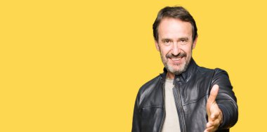 Siyah deri giyen orta yaş yakışıklı adam tebrik ve davet edici olarak gülümseyen dostu sunan karşılıklı ceket. Başarılı iş.