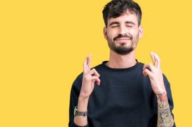 Yakışıklı delikanlı geçiş parmakları umut ve gözleri kapalı ile gülümseyen izole arka plan üzerinde. Şans ve batıl kavramı.