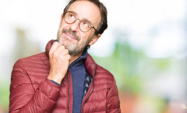 Çene düşünme hakkında soru, dalgın ifade üzerine gözlük ve el ile kış ceket giyen orta yaş yakışıklı adam. Düşünceli yüzüyle gülümsüyor. Şüphe kavramı.