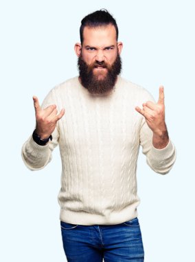 Kış kazak giyen genç hipster adam elleri ile kaya sembolü yapıyor çılgın ifade bağırıyor. Müzik yıldızı. Ağır kavram.