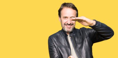 Siyah deri ceket ile büyük ve büyük boy işaret, ölçü birimi sembol gösteren el eller giyen orta yaş yakışıklı adam. Kameraya bakarak gülümsüyordu. Ölçüm kavramı.