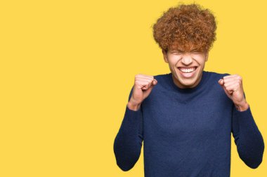 Silah ile başarı için heyecanlı afro saçlı yakışıklı delikanlı zafer kutluyor gülümseyen kaldırdı. Kazanan kavramı.