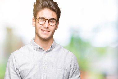 Seksi bir ifadeyle, neşeli ve mutlu yüzünü kameraya bakarak göz kırpıyor izole arka plan üzerinde gözlük takan genç yakışıklı adam.