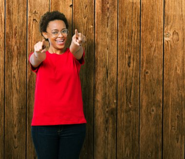 Güzel genç Afro-Amerikan kadın gözlük izole üzerinde arka plan size işaret ve parmaklar, olumlu ve neşeli gülümseyen kamerayla