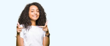 Fotoğraf makinesi ile mutlu ve komik yüz için rahat beyaz t-shirt işaret parmakları ile kıvırcık saçlı Genç güzel kız. İyi enerji ve vibes.