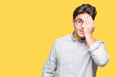 El yüz ve sürpriz duygu kendinden emin gülümseme ile tek gözüyle kapsayan izole arka plan üzerinde gözlük takan genç yakışıklı adam.