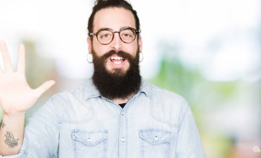 Uzun saç ve sakal gösterilen ve parmakları ile işaret gözlüklü genç hipster adamla beş kendinden emin ve mutlu gülümseyerek iken numara.