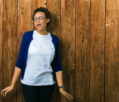 Genç güzel Afrikalı-Amerikalı kadın seksi bir ifadeyle, neşeli ve mutlu yüzünü kameraya bakarak göz kırpıyor izole arka plan üzerinde gözlük.