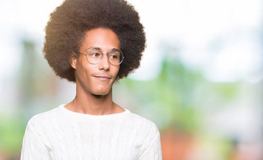 Afrikalı-Amerikalı genç afro saçlı gözlüklü uzak tarafına yüzünde, doğal ifade gülümseme ile seyir. Kendine güvenen gülüyor.