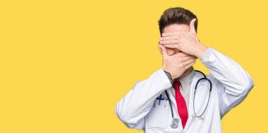 Tıbbi kat kaplama gözler ve ağız el ile giyen genç yakışıklı Doktor adam şaşırttı ve şok. Duygu gizleme