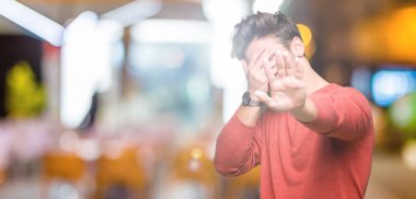 Genç yakışıklı adam izole elleriyle gözlerini kapsayan arka plan ve stop jest ile acı ve korku ifadesi. Utandım ve negatif kavramı.