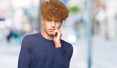 Çene düşünme hakkında soru, dalgın ifade üzerine el ile afro saçlı genç yakışıklı adam. Düşünceli yüzüyle gülümsüyor. Şüphe kavramı.