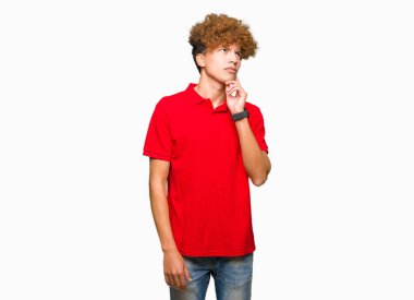 Çene düşünme hakkında soru, dalgın ifade üzerine el ile kırmızı t-shirt giyen afro saçlı Genç yakışıklı adam. Düşünceli yüzüyle gülümsüyor. Şüphe kavramı.