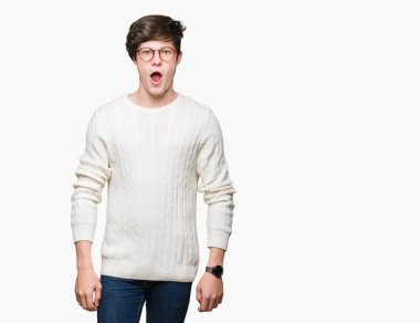 Korkuyor ve şok sürpriz ifade, korku ve heyecan yüz ile izole arka plan üzerinde gözlük takan genç yakışıklı adam.