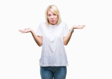 İzole arka plan clueless ve şaşkın bir ifadeyle kollar ve eller kaldırdı üzerinde beyaz t-shirt giyen genç güzel sarışın kadın. Şüphe kavramı.